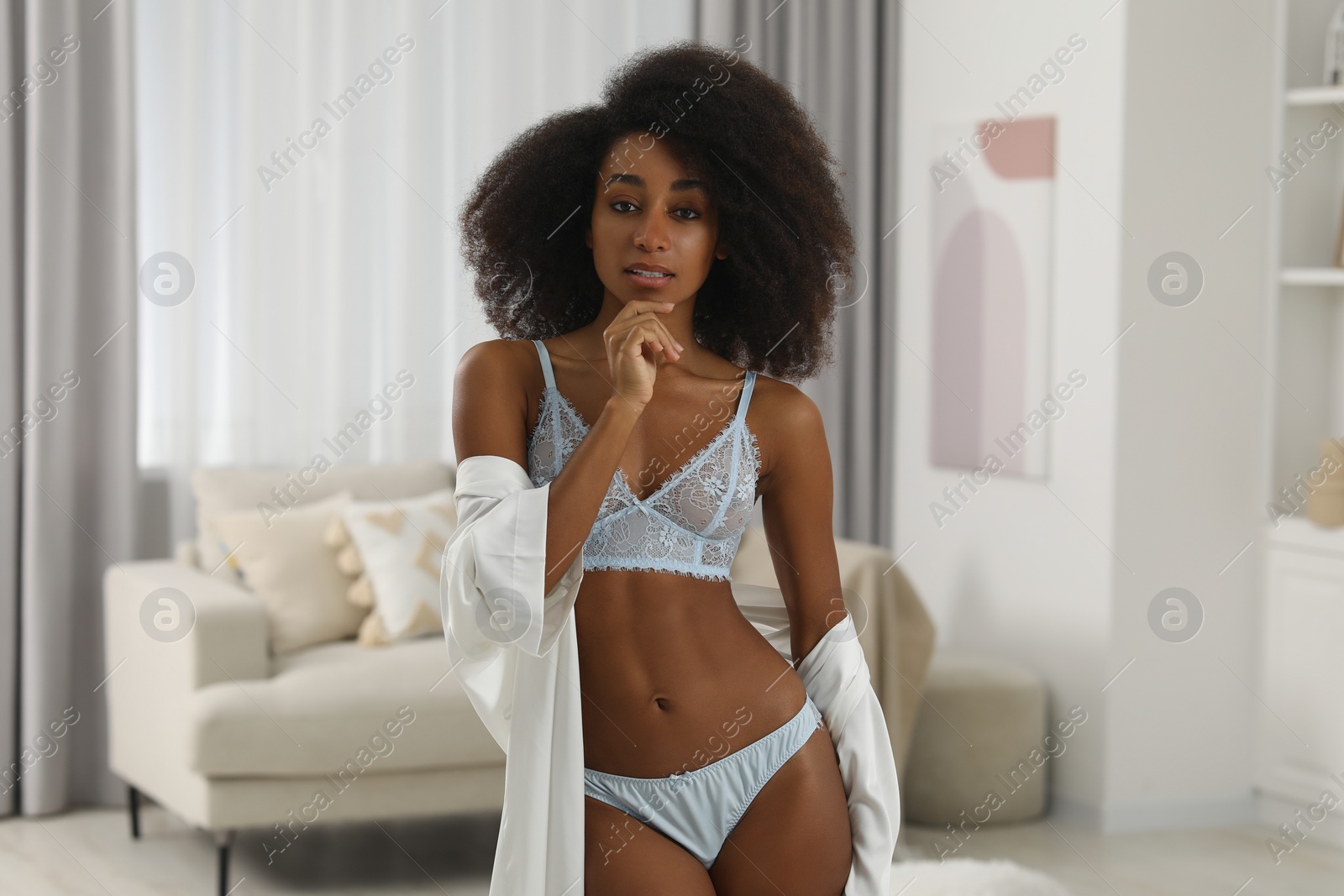 Photo of Beautiful woman in elegant light blue underwear and robe indoors