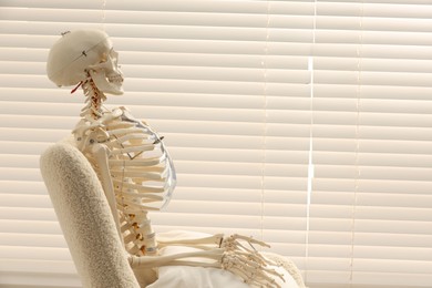 Photo of Waiting concept. Human skeleton sitting in armchair indoors, space for text