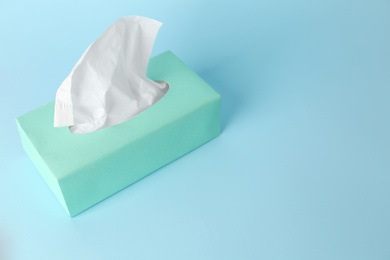 Photo of Box of paper tissues on light blue background. Space for text