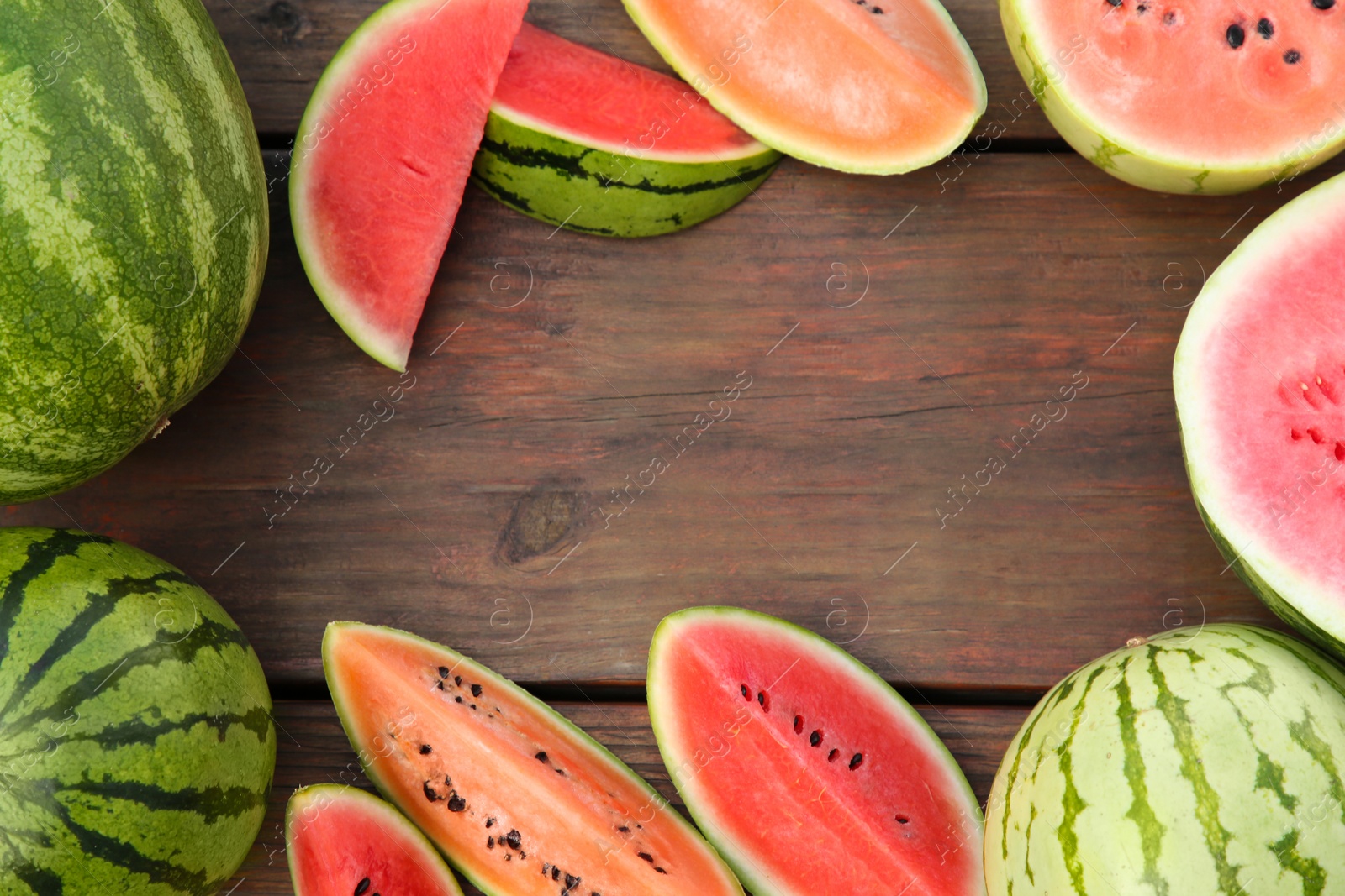 Photo of Frame made of different cut and whole watermelons on wooden table, flat lay. Space for text