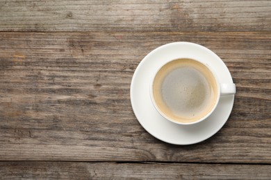 Aromatic coffee in cup on wooden table, top view. Space for text