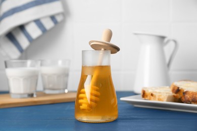 Photo of Jar with honey, milk, bread and butter on blue wooden table