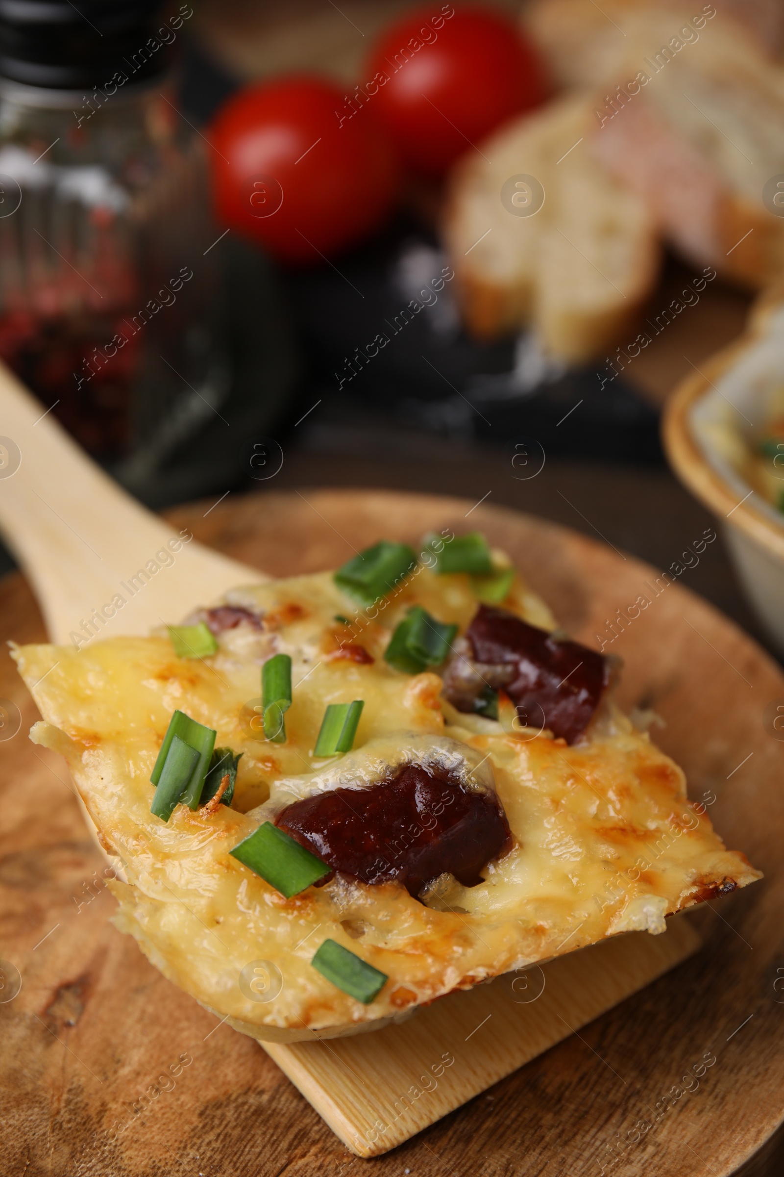 Photo of Spatula with piece of tasty sausage casserole on table, closeup