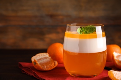 Photo of Delicious tangerine jelly in glass and fresh fruits on table, closeup