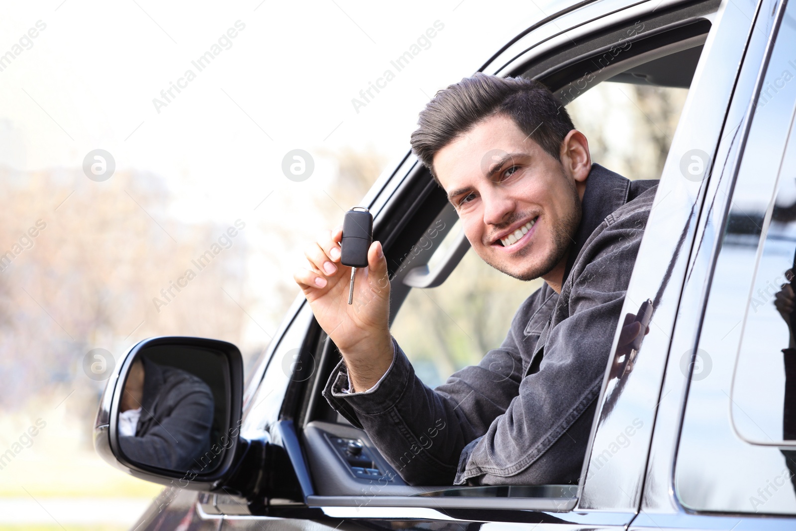 Photo of Man with key sitting in car outdoors. Buying new auto