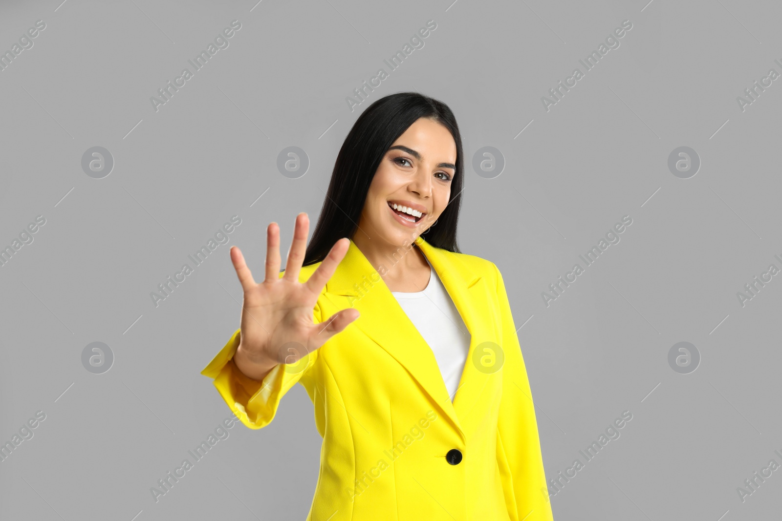 Photo of Woman showing number five with her hand on grey background