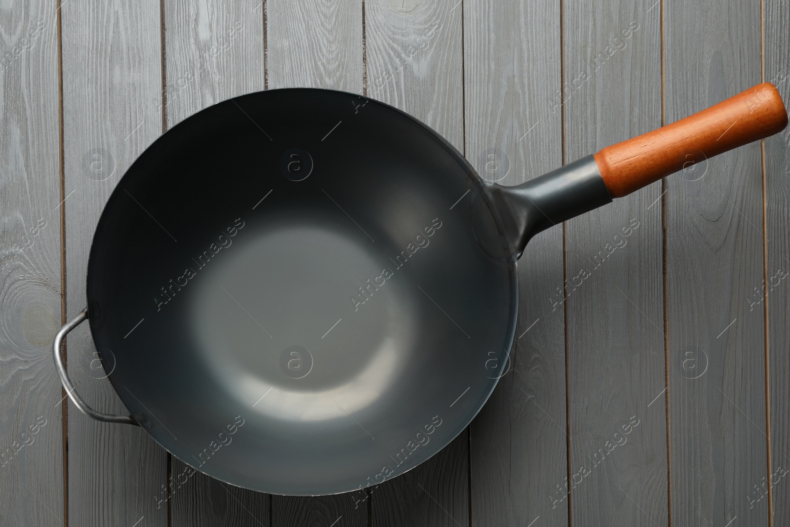 Photo of Empty iron wok on grey wooden table, top view. Chinese cookware