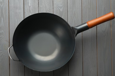 Photo of Empty iron wok on grey wooden table, top view. Chinese cookware