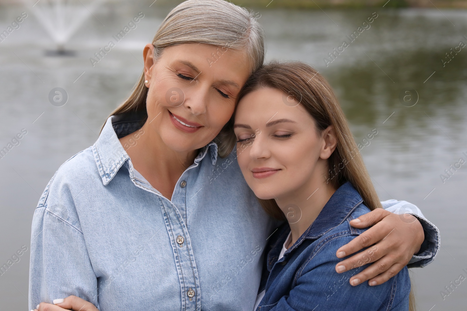 Photo of Happy mature mother and her daughter near pond