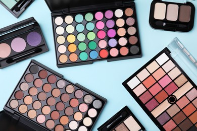 Photo of Flat lay composition with beautiful eye shadow palettes on light blue background