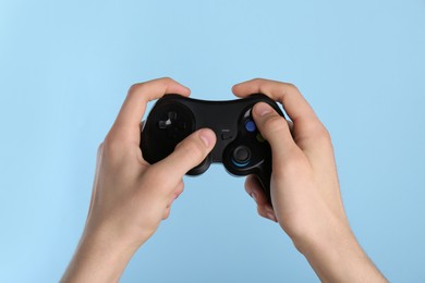 Photo of Man using wireless game controller on light blue background, closeup