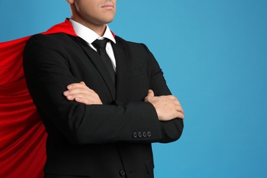 Man wearing superhero cape on light blue background, closeup