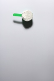 Photo of Scoop of protein powder on light background, top view with space for text