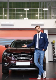 Photo of Salesman standing in modern auto dealership. Buying new car