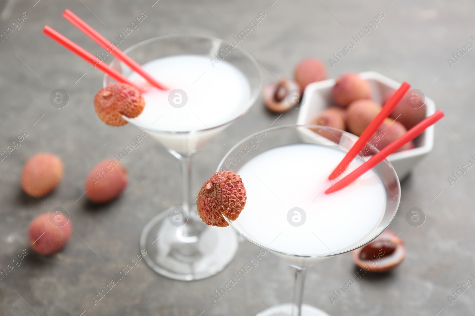 Photo of Lychee cocktail with fresh fruits on grey table, closeup