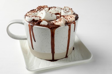 Photo of Delicious hot chocolate with marshmallows and cocoa powder in cup on white table, closeup