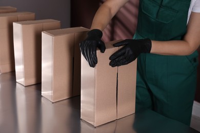 Photo of Woman packing cardboard boxes at production line, closeup