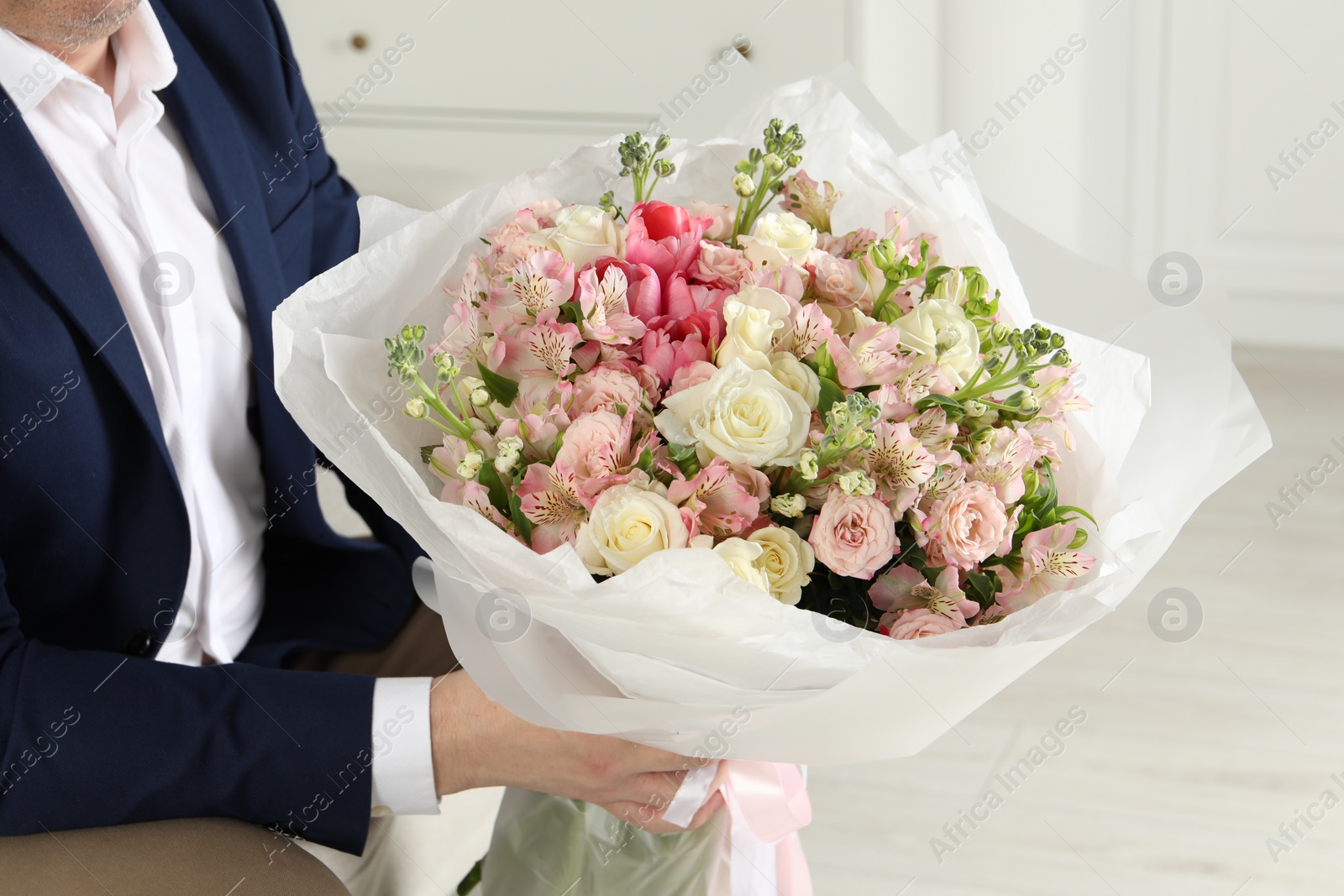 Photo of Man with beautiful bouquet of flowers indoors, closeup