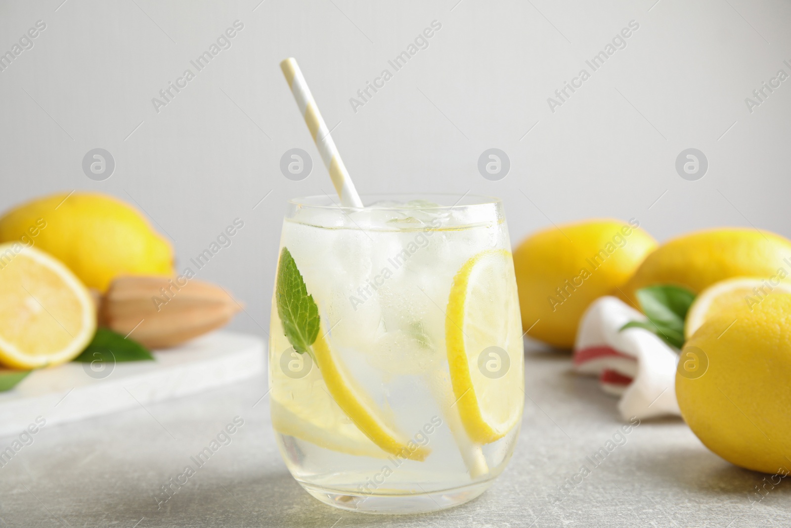 Photo of Glass of cold lemonade on light grey table, closeup