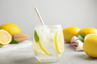 Glass of cold lemonade on light grey table, closeup