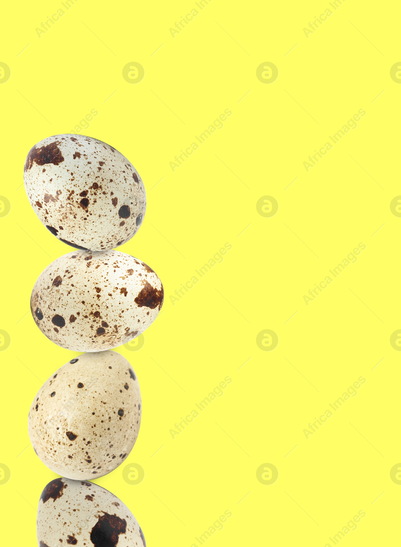 Image of Stacked speckled quail eggs on light yellow background. Space for text