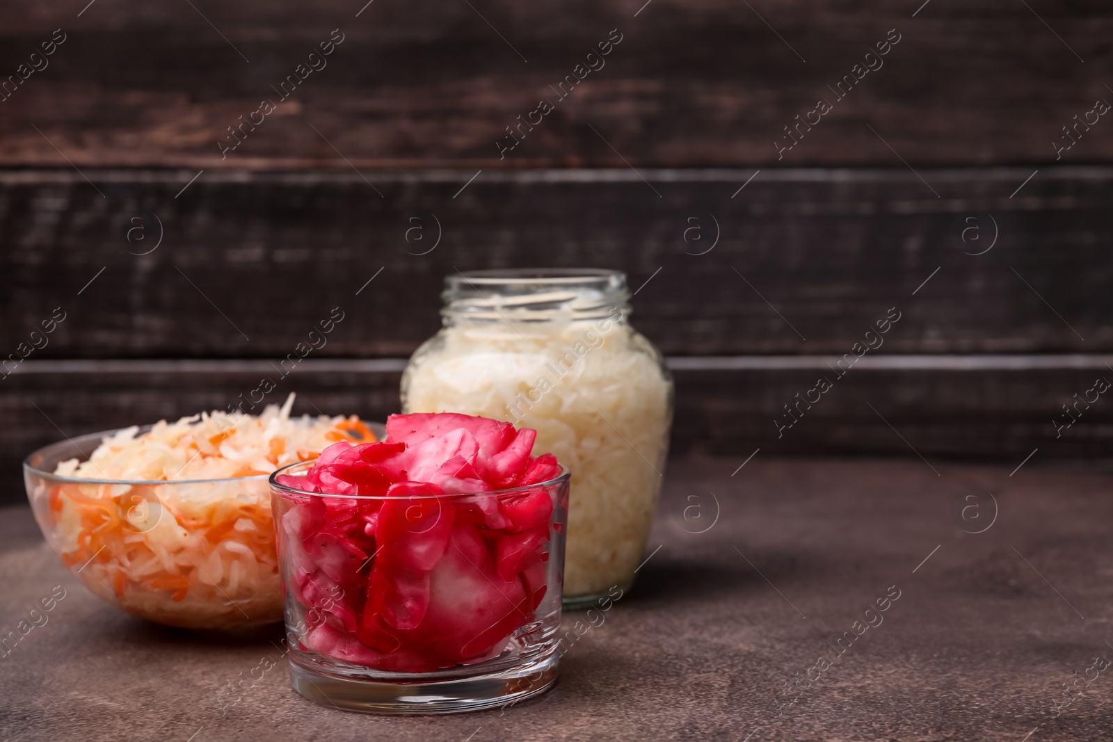 Photo of Delicious sauerkraut prepared according to different recipes on brown table, space for text