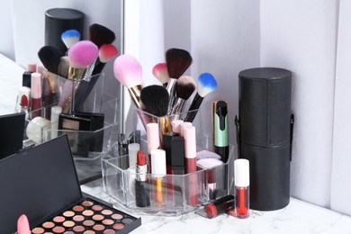 Photo of Bright lip glosses among different cosmetic products on white dressing table