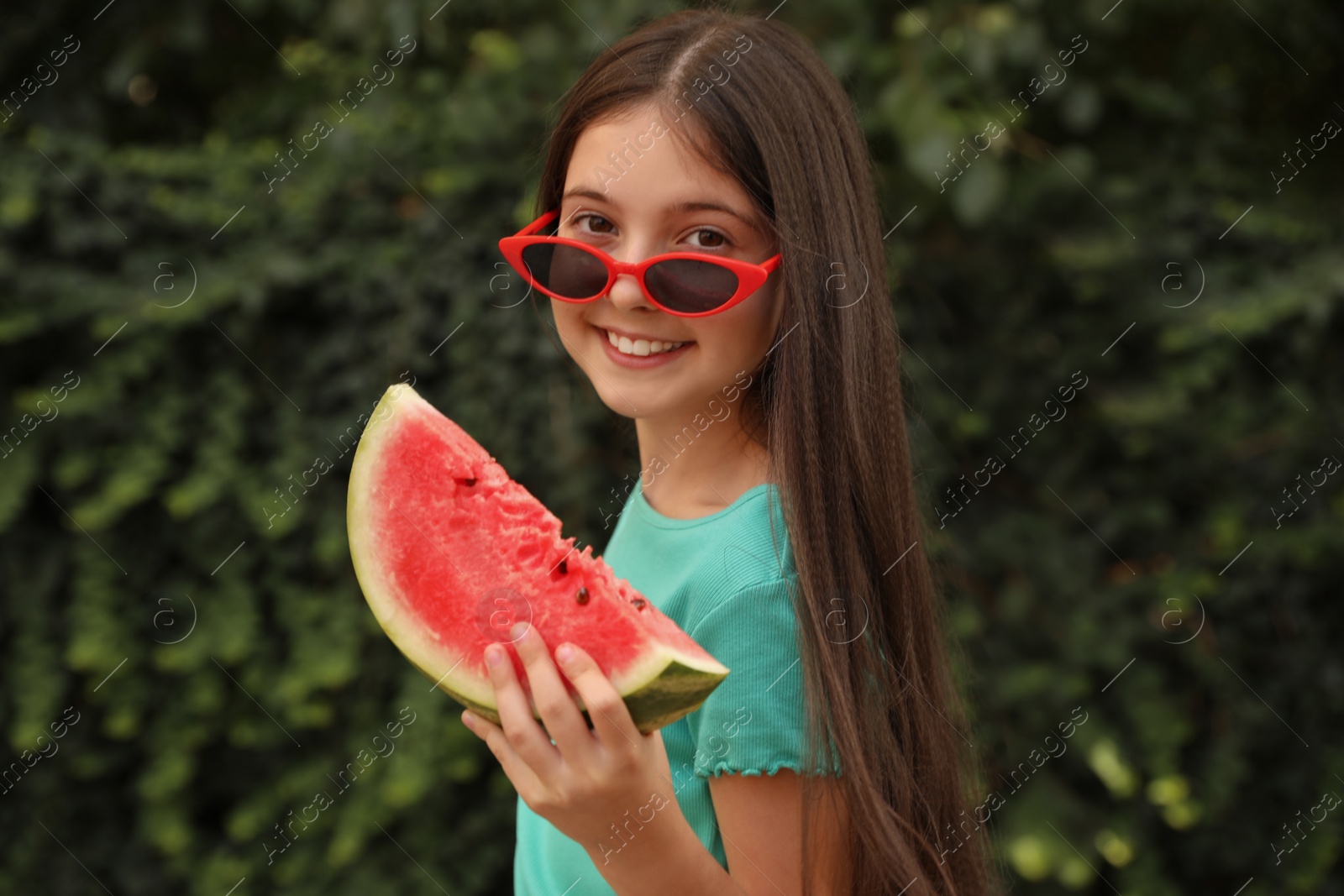 Photo of Cute little girl with watermelon outdoors on sunny day