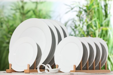 Set of clean dishware on white table against blurred background