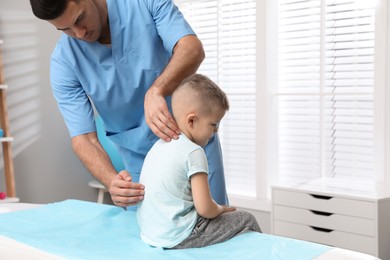 Photo of Orthopedist examining child's back in clinic. Scoliosis treatment