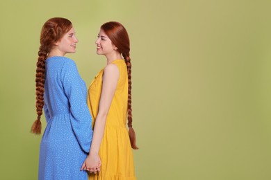 Portrait of beautiful young redhead sisters with braided hair on pink background. Space for text