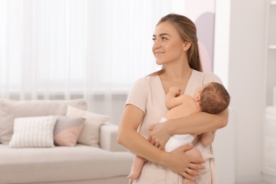 Mother holding her cute newborn baby at home, space for text