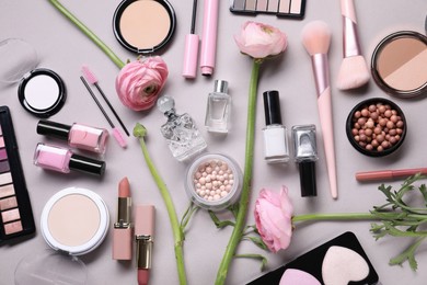 Flat lay composition with different makeup products and beautiful spring flowers on gray background