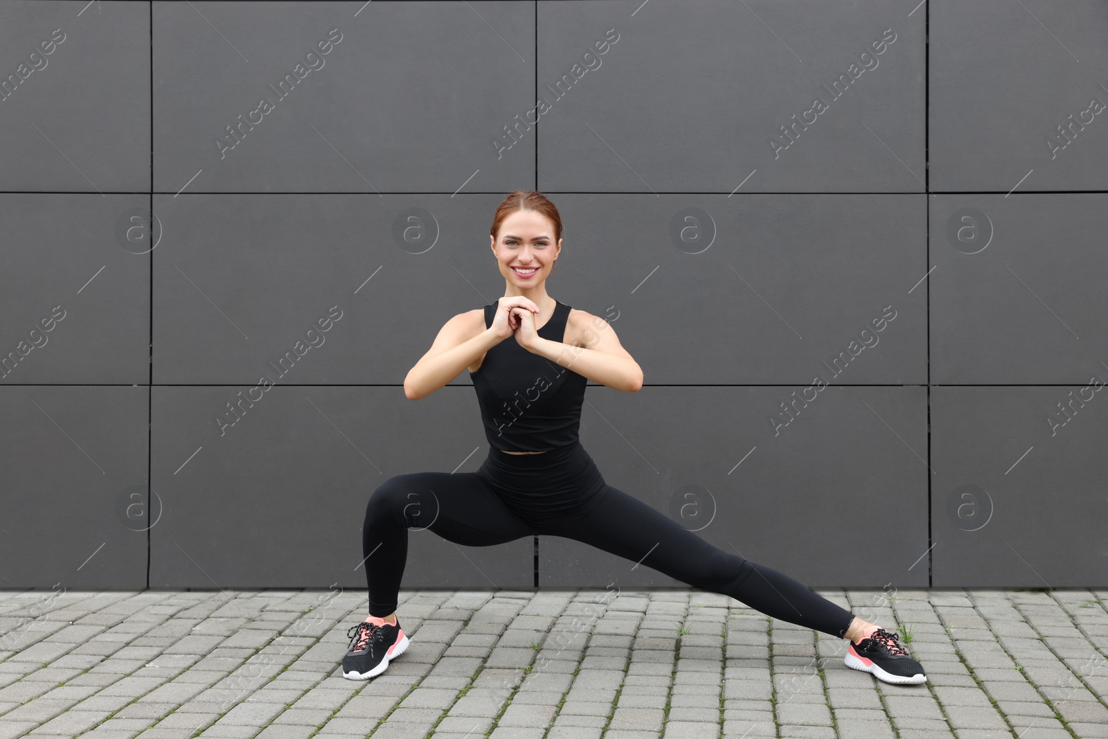 Photo of Beautiful woman in gym clothes doing exercises on street