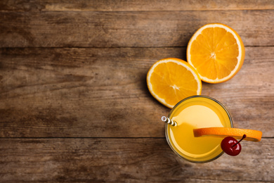 Photo of Fresh alcoholic Tequila Sunrise cocktail on wooden table, flat lay. Space for text