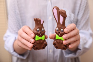 Photo of Woman with chocolate Easter bunnies on beige background, closeup