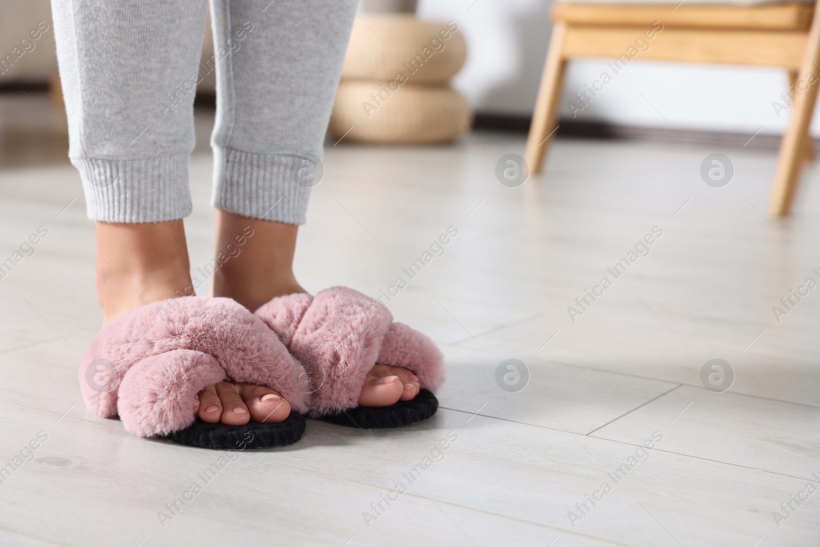 Photo of Woman wearing soft slippers at home, closeup of legs