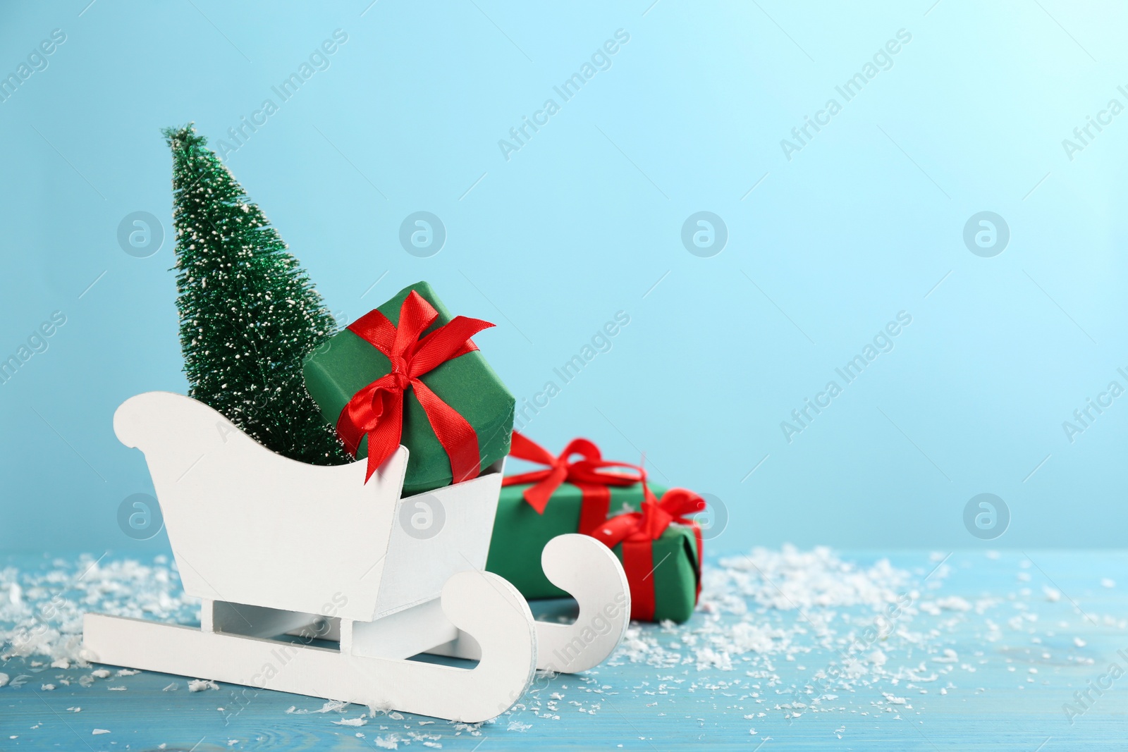 Photo of Beautiful Christmas composition with miniature sleigh on light blue table. Space for text