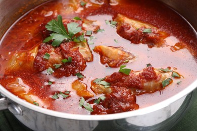 Photo of Delicious stuffed cabbage rolls cooked with homemade tomato sauce in pot, closeup