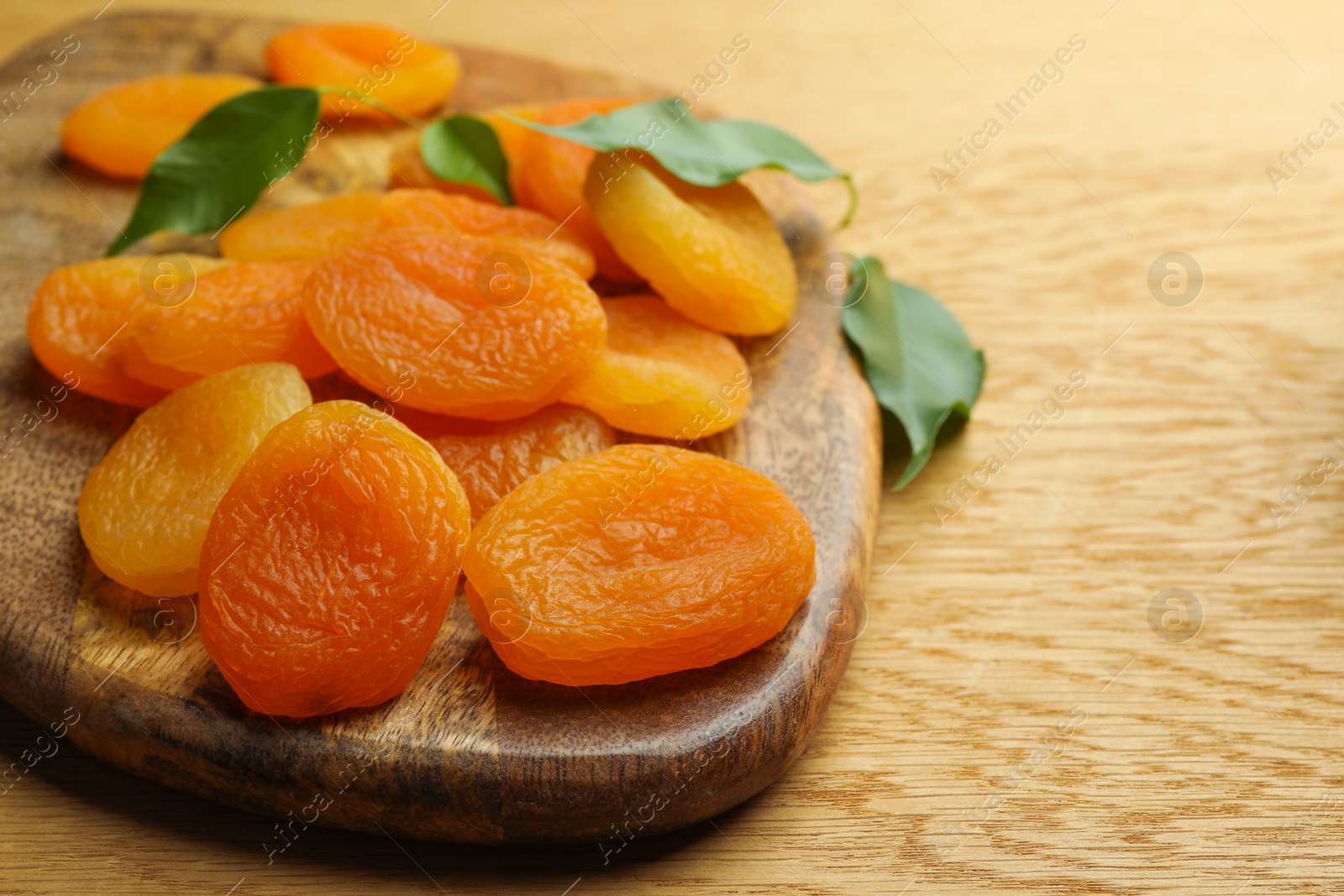 Photo of Closeup view of tasty apricots on wooden table, space for text. Dried fruits