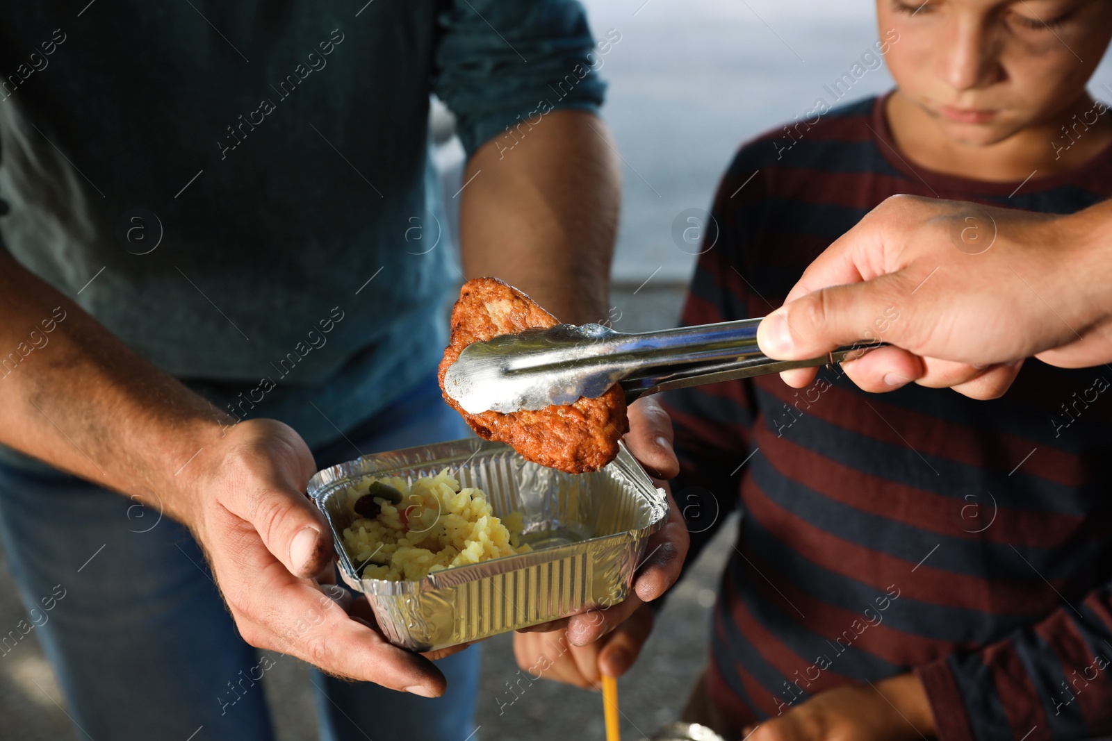 Photo of Poor people receiving food from volunteer outdoors, closeup