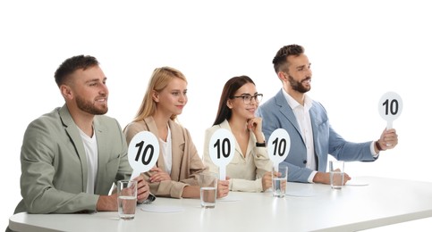 Photo of Panel of judges holding signs with highest score at table on white background