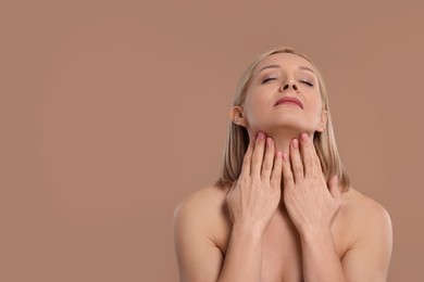 Photo of Beautiful woman touching her neck on beige background, space for text