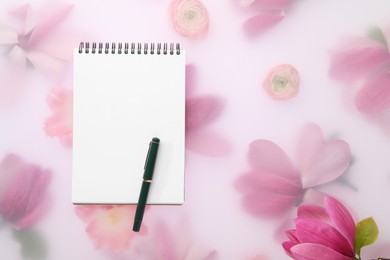 Guest list. Notebook, pen and magnolia on spring floral background, flat lay. Space for text