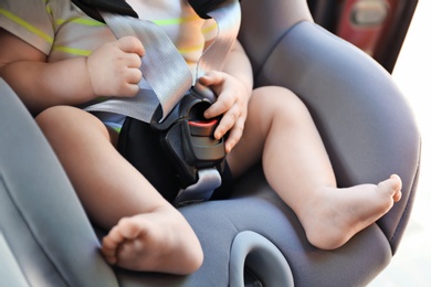 Photo of Little baby in child safety seat inside of car, closeup on legs