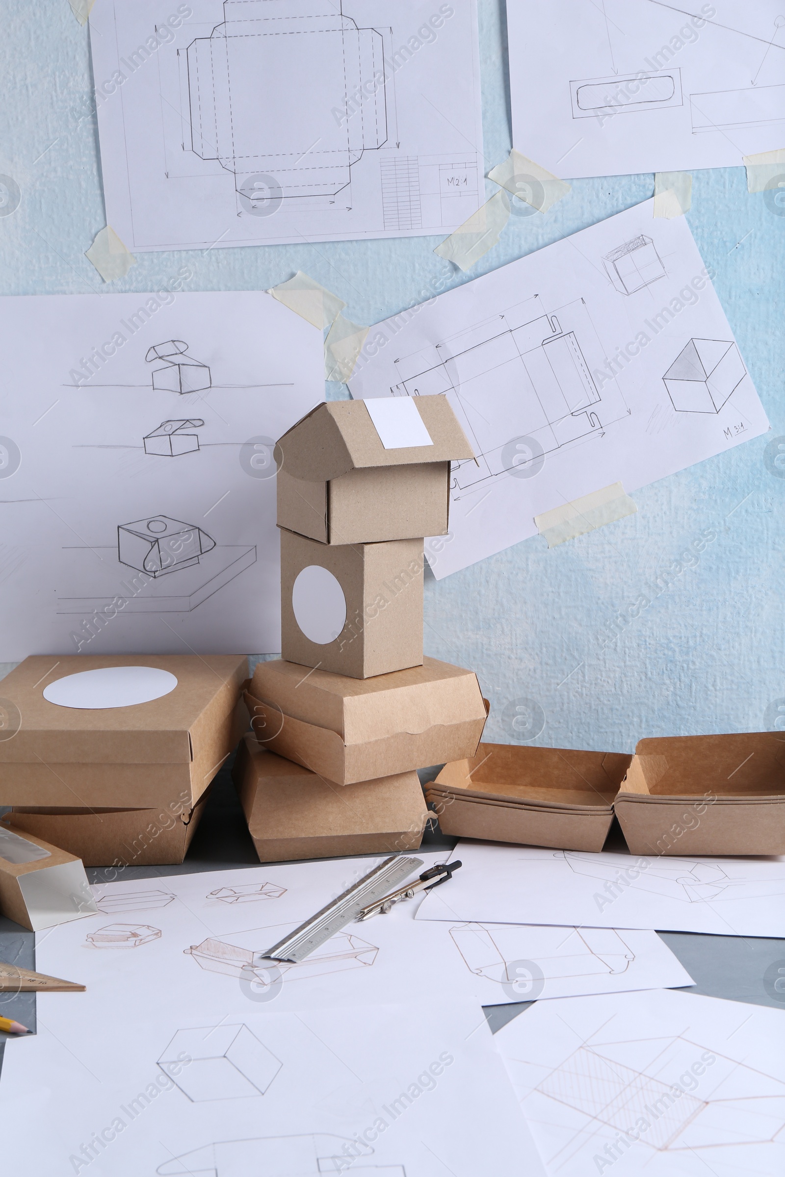 Photo of Creating packaging design. Drawings, boxes and stationery on table, closeup