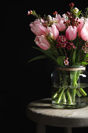 Photo of Beautiful bouquet with spring pink tulips on wooden table against black background