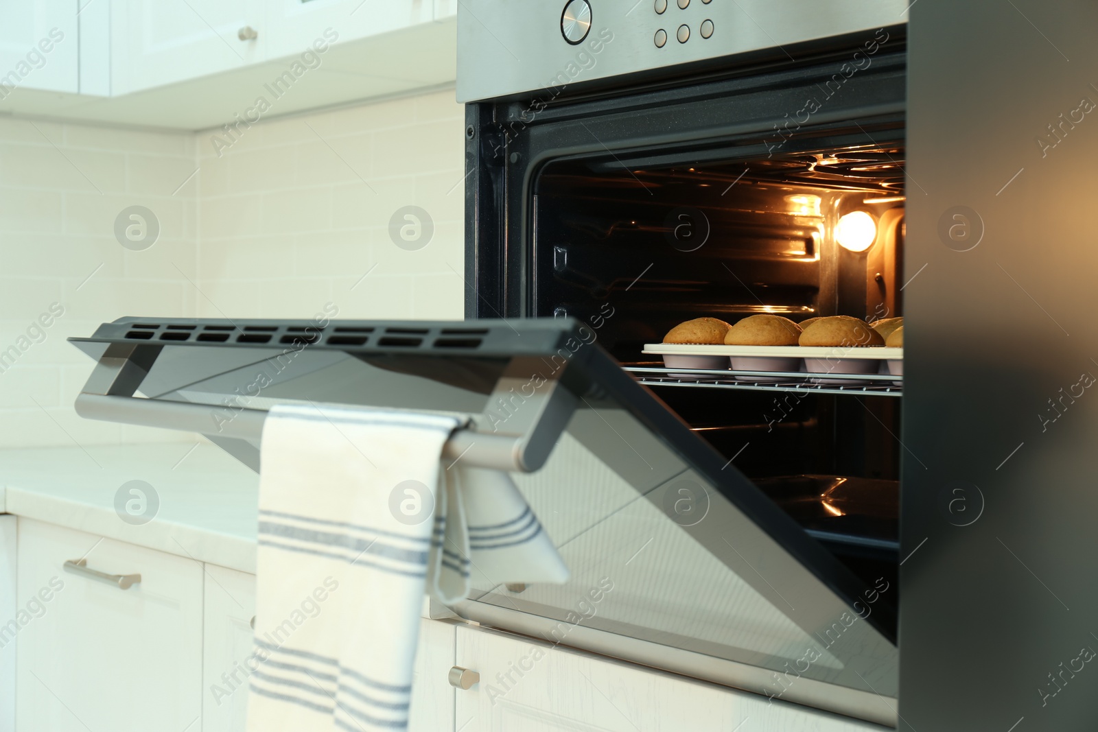 Photo of Baking pan with cupcakes in modern oven