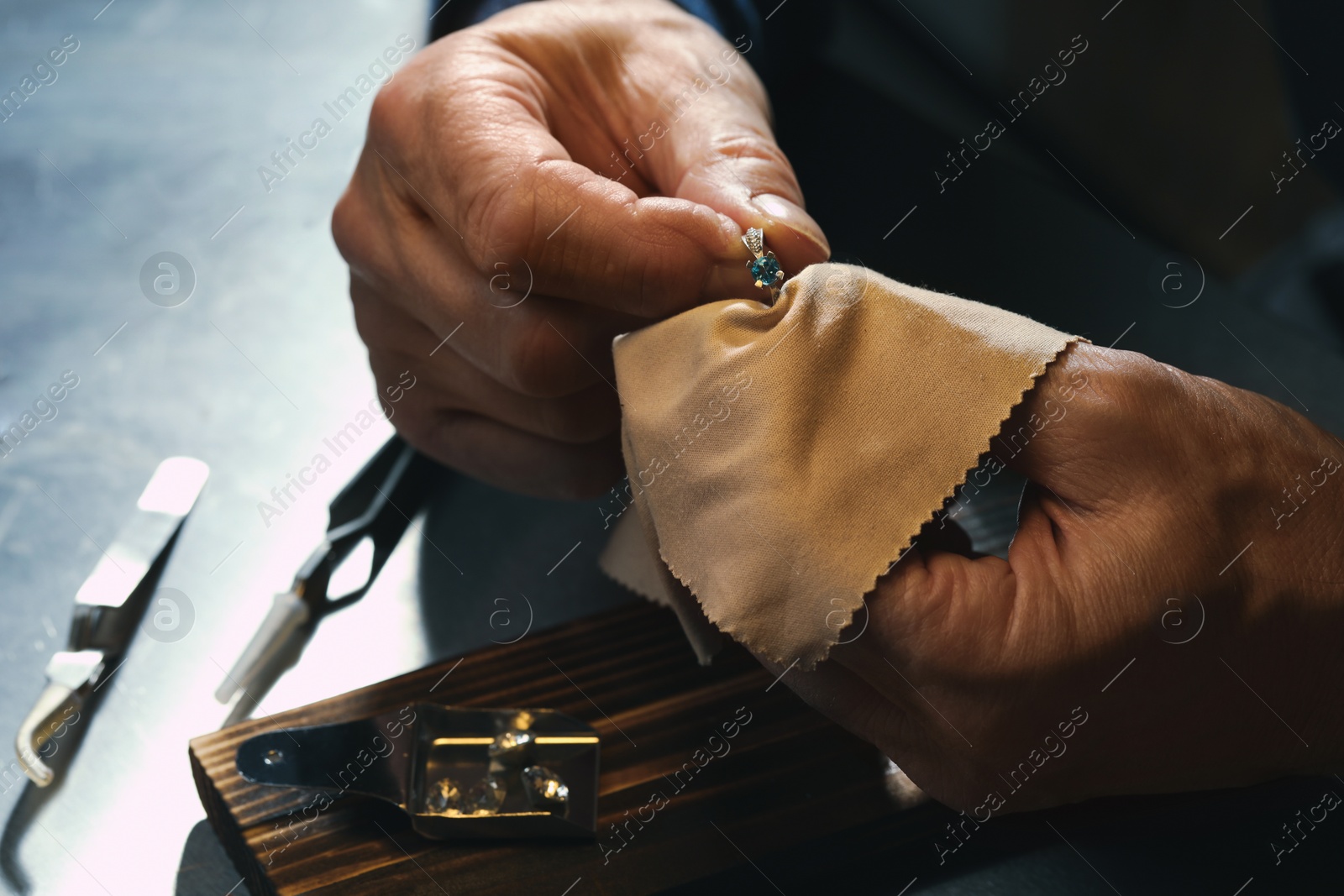 Photo of Professional jeweler working with ring at table, closeup