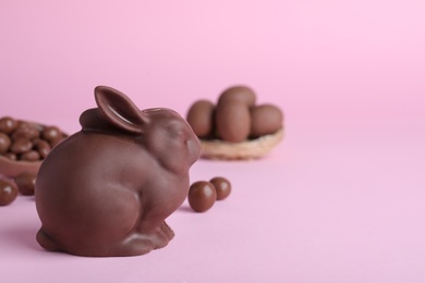 Photo of Chocolate Easter bunny and candies on pink background. Space for text